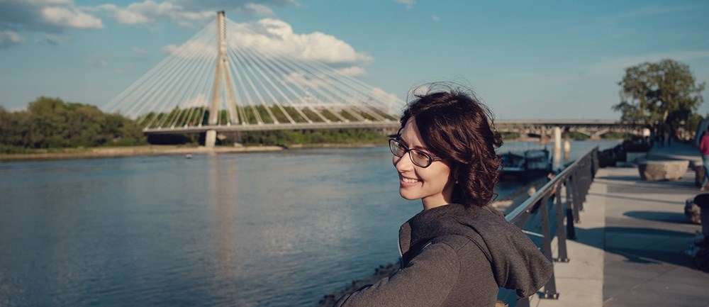 En kvinna tittar leende ut över floden Wisla i Warsawa. 