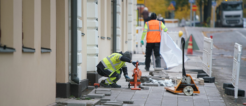 Två unga byggarbetare lägger gatsten i Åbo. 
