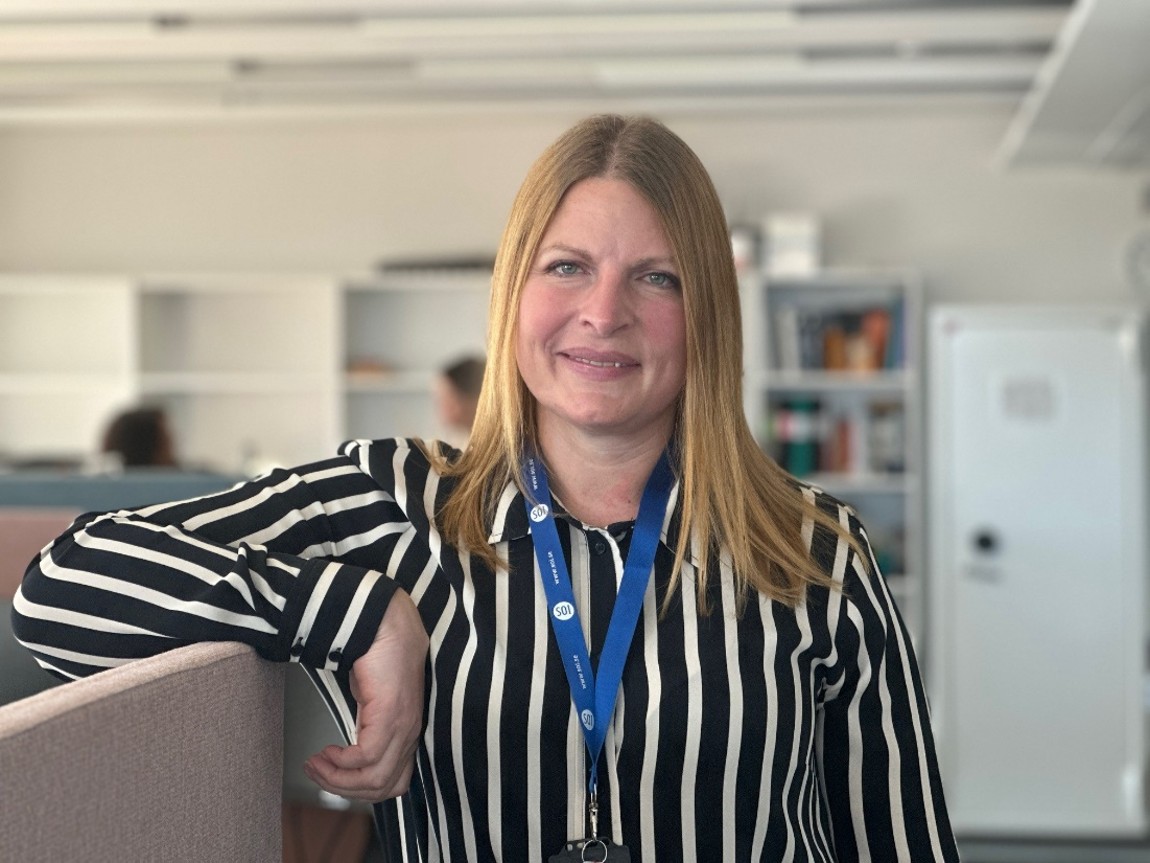 Helena Sk&ouml;ld L&ouml;vgren st&aring;r vi en soffa p&aring; kontoret.