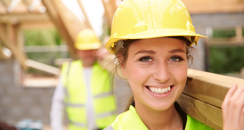 En kvinnlig och en manlig byggnadsarbetare på en byggarbetsplats
