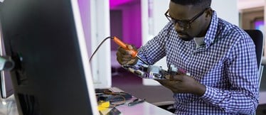 En tekniker reparerar en dators moderkort. 