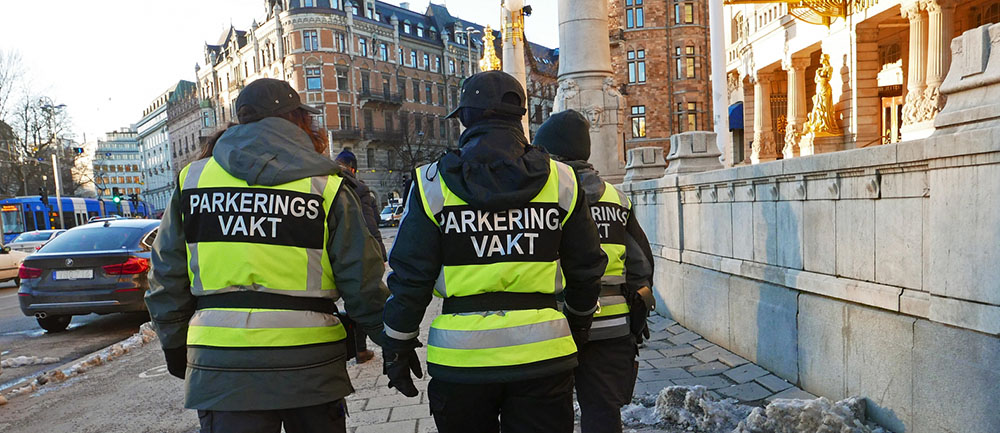 Tre parkeringsvakter promenerar förbi Dramaten i Stockholm.