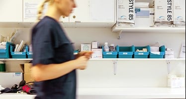 Sjuksköterska under arbetspass går förbi förbrukningsmaterial