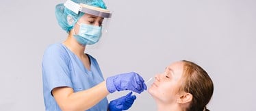 Sjuksköterska med skyddsmaterial tar näsprov på patient
