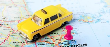 En liten gul taxibil ovanpå en karta. 