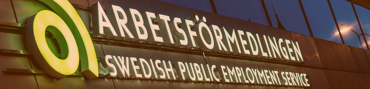 Arbetsförmedlingens logotyp lyser på en husfasad.
