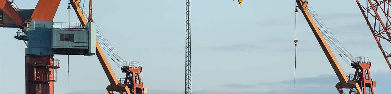 Flera lyftkranar mot blå himmel