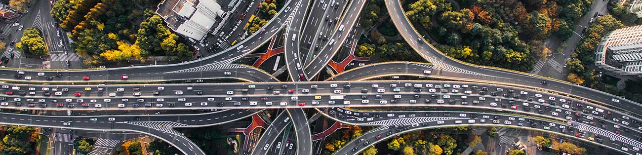 Infrastruktur med byggnader och sammankopplade vägnät som trafikeras av många fordon fotograferat ovanifrån