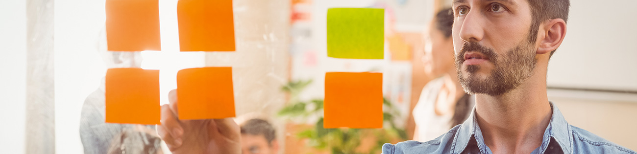 En man sätter upp post-it-lappar på en glasvägg.
