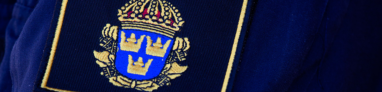 Säkerhetspolisens logga på en blå skjorta.